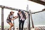 Young couple ducking under old pier, Cape Town, Western Cape, South Africa