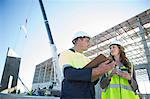 Site manager with clipboard meeting architect on construction site