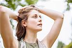 Serene young woman gazing up with hands in hair