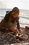 Woman making a fire by seaside