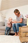 Mature mother sharing drink with baby daughter in sitting room