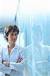 Portrait of mature businesswoman leaning against glass wall in office