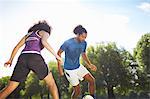 Young couple playing soccer in park