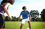 Young couple playing soccer together in park