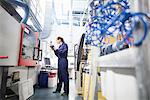 Female engineer monitoring automated machinery using digital tablet