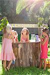 Four girls buying and selling at lemonade stand in park