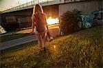 Rear view of young woman walking near bridge and riverside