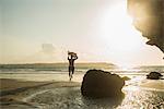 Mature man running towards sea, holding surf board