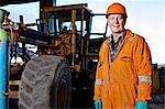 Portrait of quarry worker next to excavator at quarry site