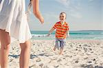 Mid adult mother playing with young son on beach, Cape Town, Western Cape, South Africa