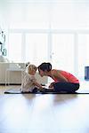 Mid adult mother and toddler daughter practicing lotus position in living room