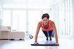 Mid adult woman doing press ups in living room