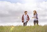 Young couple running through meadow under bright sunshine