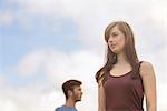 Young couple standing apart and looking away under bright blue sky