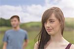 Young couple standing apart and looking away in rural landscape, close up