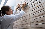 Pharmacist in pharmacy filing medicine away in drawer