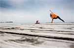 Mid adult woman practicing yoga position on wooden sea pier