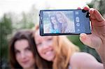 Close up of two young female friends taking selfie on smartphone in park