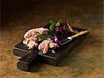 Christmas snack of chicken & ham terrine with red onions, bay and basil leaves on chopping board