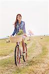 Teenager riding bicycle on field, Roznov, Czech Republic