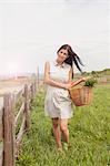 Young woman with basket of vegetable on field, Roznov, Czech Republic