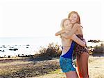 Portrait of two young women friends hugging on beach, Williamstown, Melbourne, Australia