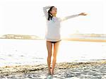 Young woman on sunlit beach with arm out, Port Melbourne, Melbourne, Victoria, Australia