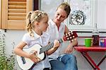 Girl playing guitar with mother