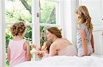 Mother and three daughters looking out of window