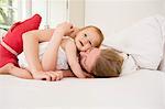 Mother hugging baby daughter on bed