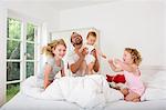 Father playing with daughters on bed