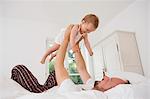 Father playing with baby daughter on bed