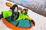 Boy laughing whilst tobogganing down snowy hill