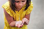 Girl holding and looking down at worm