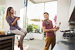 Couple laughing and fooling around whilst cooking in kitchen