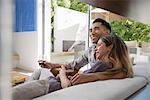 Couple relaxing together with glass of red wine on sitting room sofa