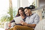 Couple on sitting room sofa looking at digital tablet