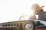 Two young women standing up in back of jeep