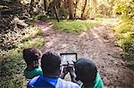 Father with daughter and son navigating with digital tablet in forest eco camp