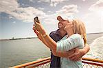 Mature couple photographing themselves on passenger ferry deck