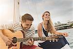 Young couple on sailing boat, man playing guitar