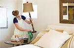 Young woman cleaning bedroom with green cleaning products