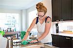 Young woman cleaning kitchen with green cleaning products