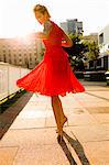 Young woman twirling whilst wearing red dress