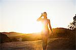 Female jogger drinking in sunlight, Poway, CA, USA