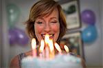 Mature woman holding birthday cake with candles