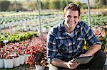 Portrait of young male worker using digital tablet in plant nursery polytunnel