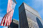 Low angled view of skyscrapers and American flag in financial district, Manhattan, New York, USA