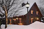 Reconstructed 1840s residential log home with Christmas decorations at dusk, Quebec, Canada