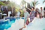 Happy family with two children walking by resort swimming pool